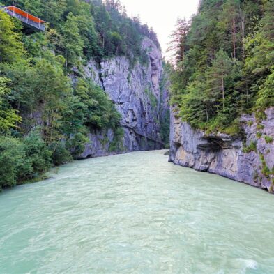 Majestic waterfall cascading down the rocky cliffs of the Swiss Alps surrounded by dense forest