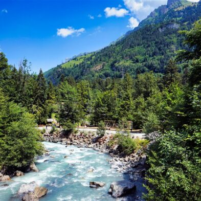 Winding road over Furka Pass with dramatic views of the Swiss Alps and distant glaciers