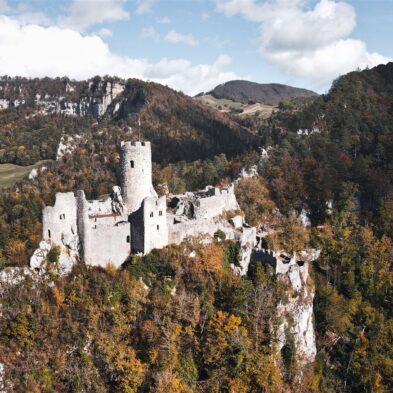 Sunrise casting warm golden light over the towering peaks of the Swiss AlpsTraditional Swiss village nestled in a green valley with alpine slopes rising in the background