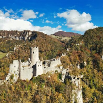 Sunrise casting warm golden light over the towering peaks of the Swiss AlpsTraditional Swiss village nestled in a green valley with alpine slopes rising in the background