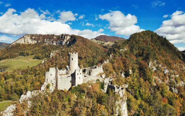 Sunrise casting warm golden light over the towering peaks of the Swiss AlpsTraditional Swiss village nestled in a green valley with alpine slopes rising in the background