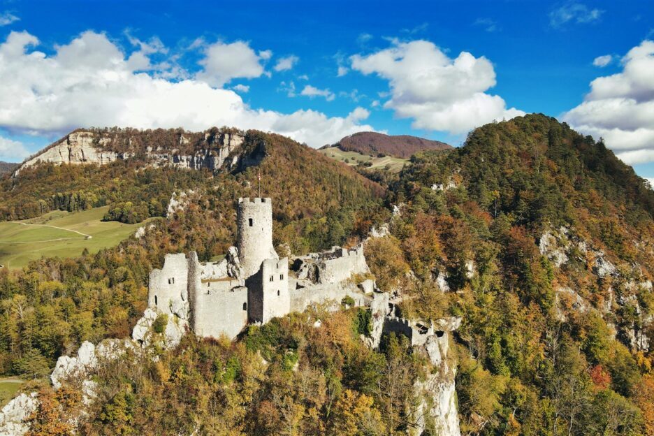 Sunrise casting warm golden light over the towering peaks of the Swiss AlpsTraditional Swiss village nestled in a green valley with alpine slopes rising in the background