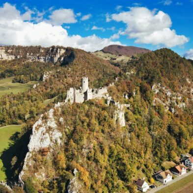 Sunrise casting warm golden light over the towering peaks of the Swiss AlpsTraditional Swiss village nestled in a green valley with alpine slopes rising in the background