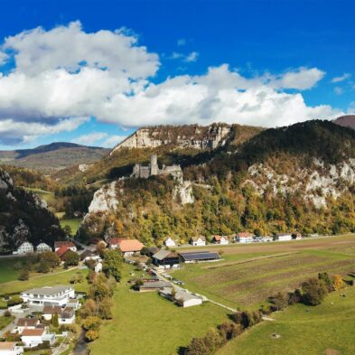 Sunrise casting warm golden light over the towering peaks of the Swiss AlpsTraditional Swiss village nestled in a green valley with alpine slopes rising in the background