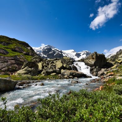 Traditional Swiss village nestled in a green valley with alpine slopes rising in the background