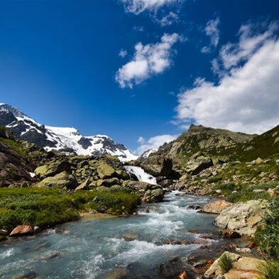 Traditional Swiss village nestled in a green valley with alpine slopes rising in the background