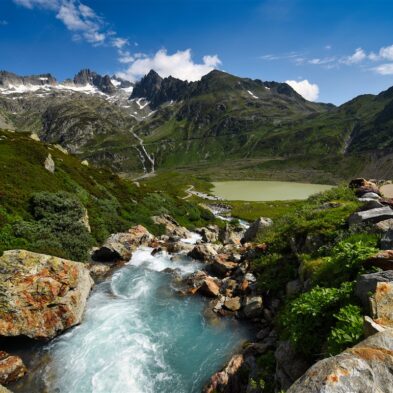 Traditional Swiss village nestled in a green valley with alpine slopes rising in the background