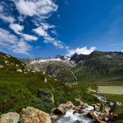 Traditional Swiss village nestled in a green valley with alpine slopes rising in the background