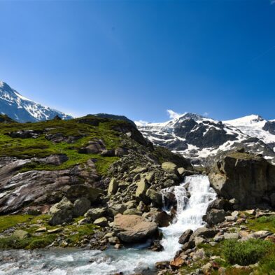 Traditional Swiss village nestled in a green valley with alpine slopes rising in the background