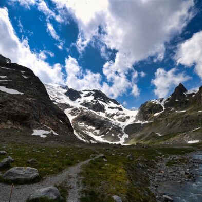 Traditional Swiss village nestled in a green valley with alpine slopes rising in the background