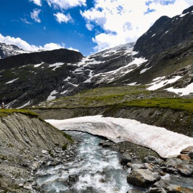 Traditional Swiss village nestled in a green valley with alpine slopes rising in the background