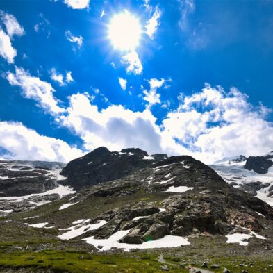 Traditional Swiss village nestled in a green valley with alpine slopes rising in the background