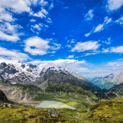 Traditional Swiss village nestled in a green valley with alpine slopes rising in the background